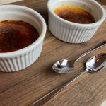 two ramekins with creme brulee and two spoons