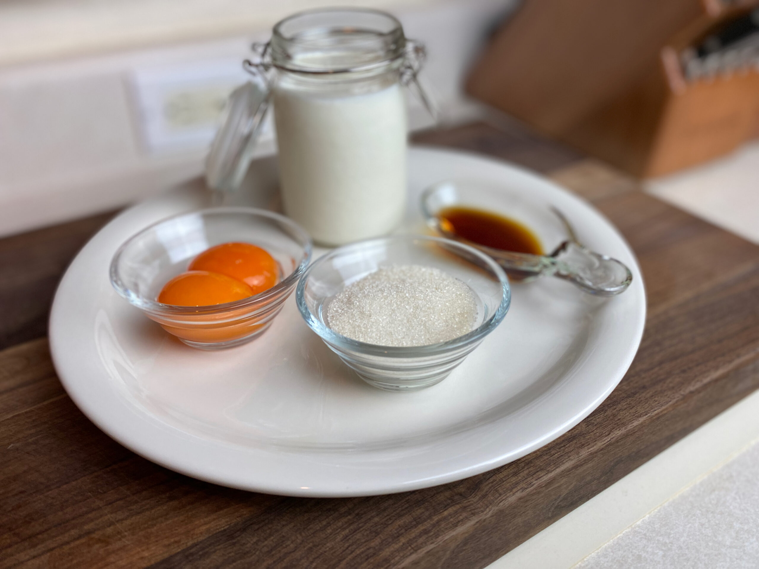 a jar of heavy cream with egg yolks, sugar, and vanilla extract