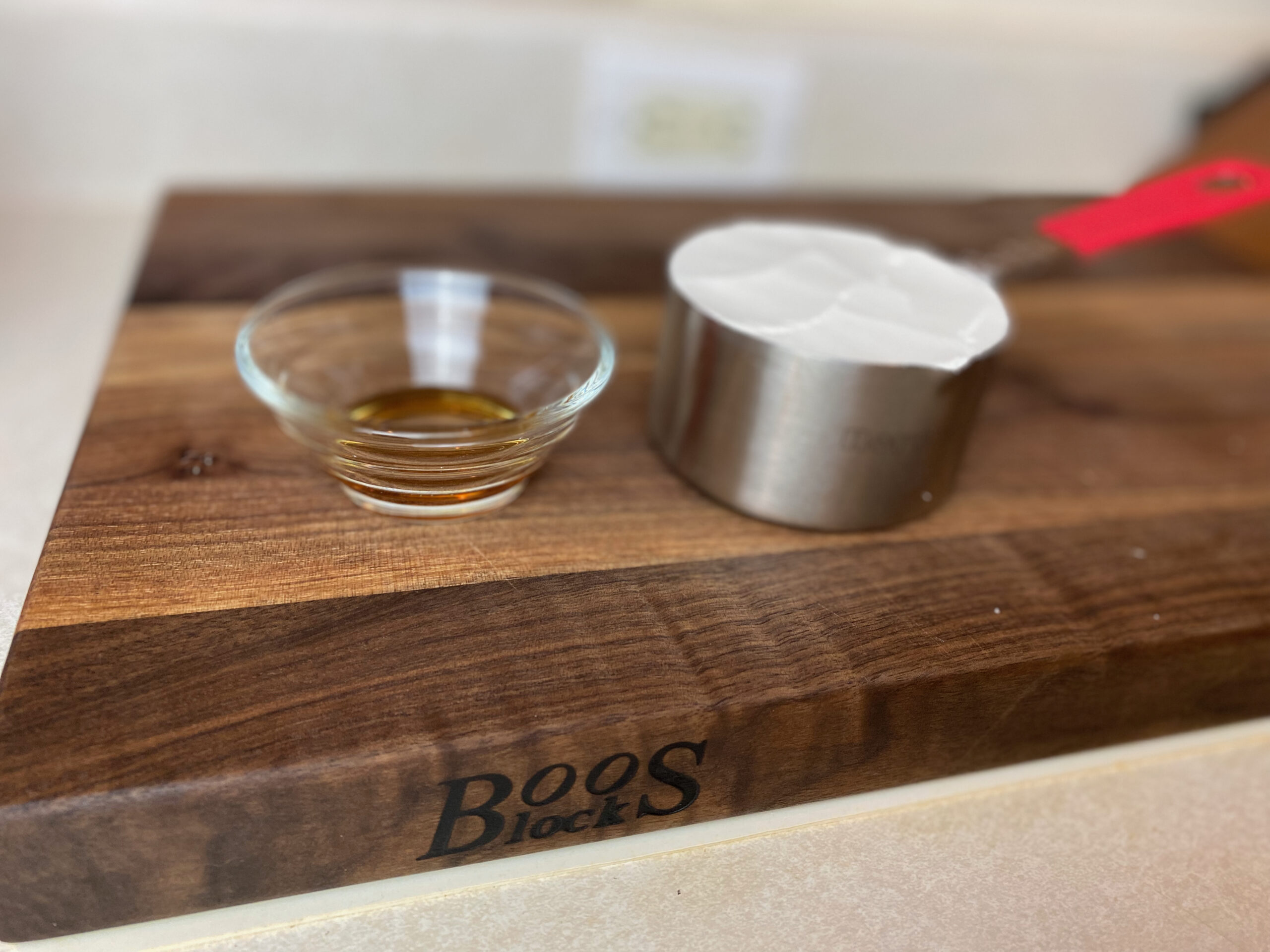 a glass cut with sesame oil, next to a measuring cup of flour