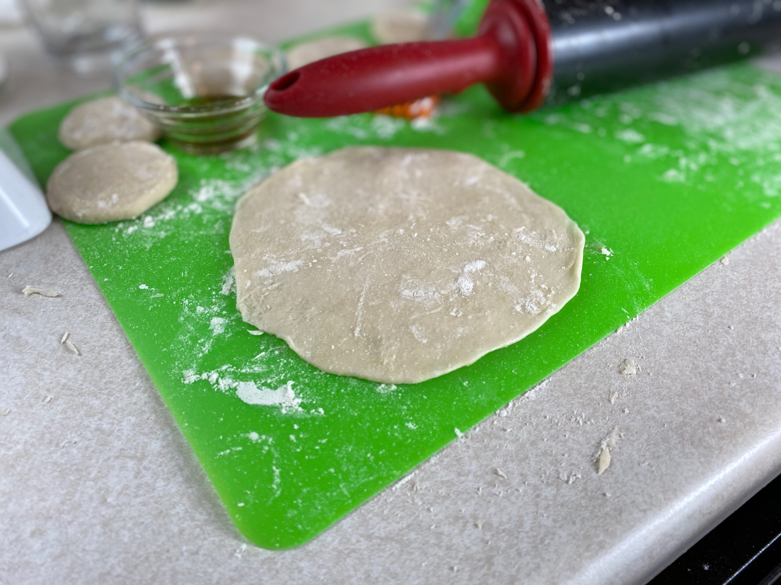 a round flattened uncooked mongolian grill crepe on a countertop