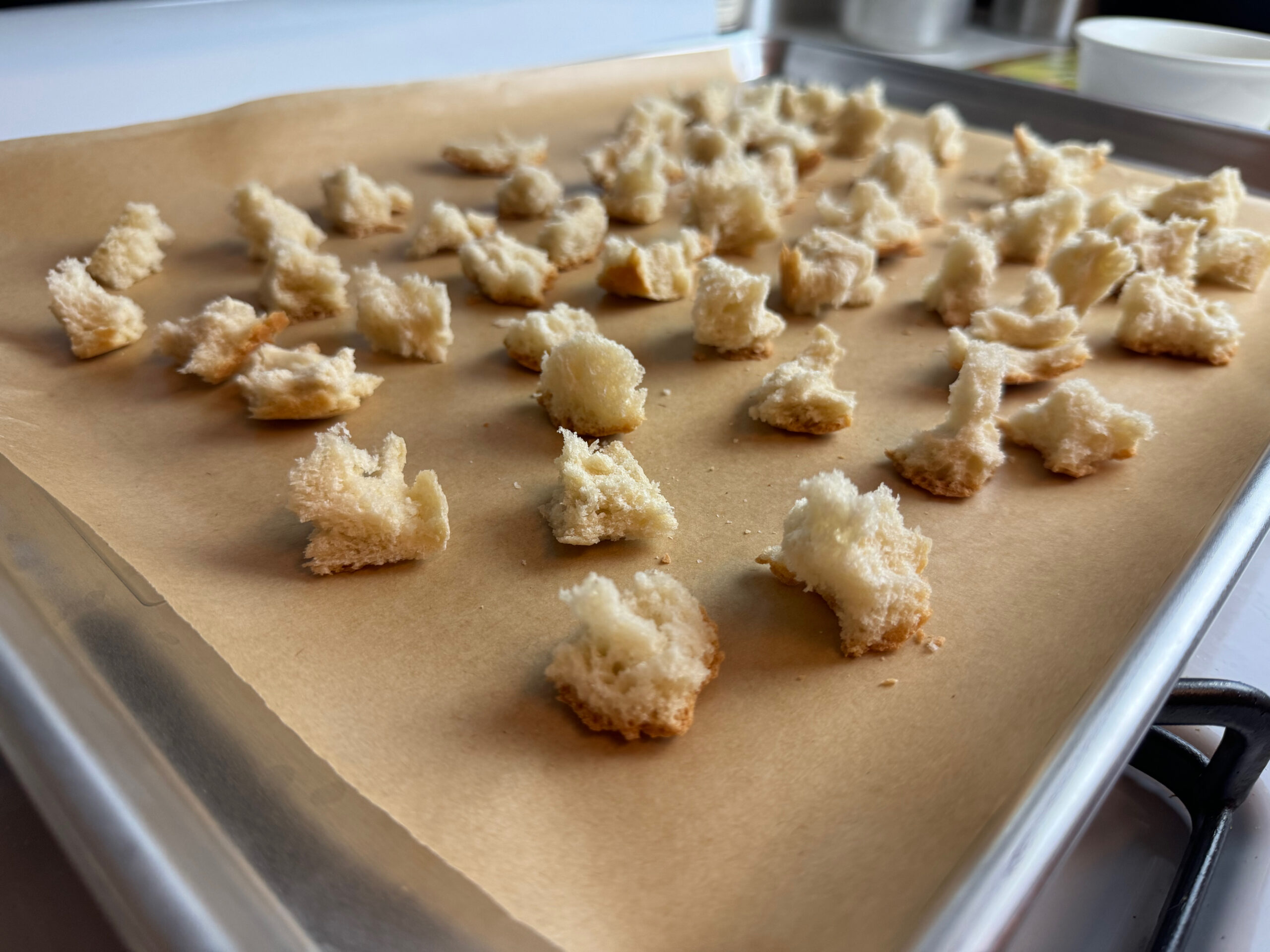 bread pieces on a baking sheet as a step to making homemade croutons