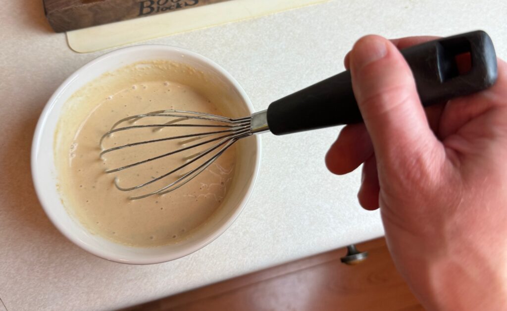 mixing the homemade Caesar dressing with a whisk
